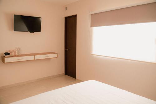 a bedroom with a bed and a television on the wall at Hotel Fratelli in Aguascalientes