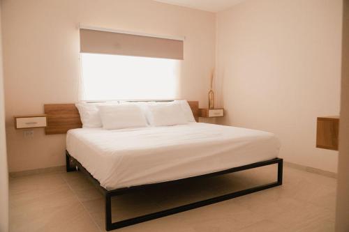 a bedroom with a white bed with a window at Hotel Fratelli in Aguascalientes