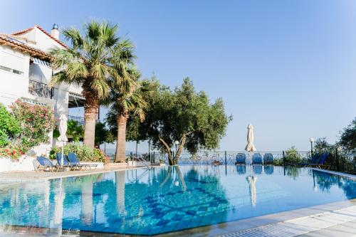 uma piscina com palmeiras e um edifício em Villa Kallithea em Parga