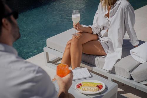 a man holding a glass of white wine and a woman sitting next to a pool at Susana Balbo Winemaker´s House in Ciudad Lujan de Cuyo