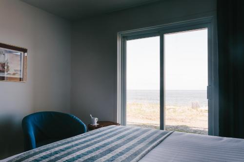 a bedroom with a bed and a view of the ocean at Pavillon sur Mer par Riôtel in Matane