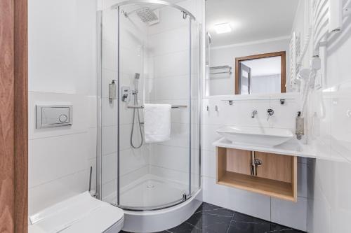 a white bathroom with a shower and a sink at Willa Letnia in Krynica Morska