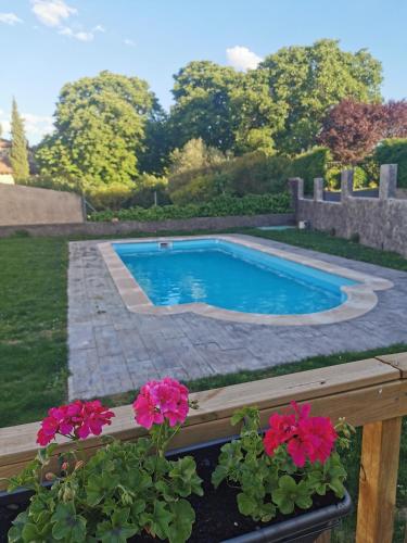 a swimming pool in a yard with pink flowers at Hotel Rural Covarrubias in Covarrubias