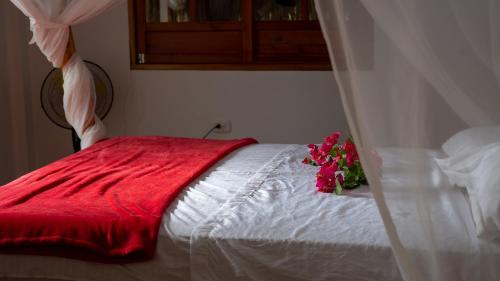 Una cama blanca con una manta roja y flores. en Rustiko Palomino Sierra Nevada, en Palomino