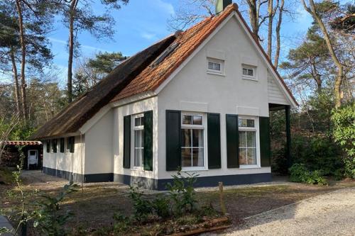una pequeña casa blanca con techo marrón en De Compaenenhorst, en IJhorst
