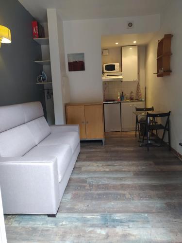 een woonkamer met een witte bank en een keuken bij Petit Studio, terrasse, jardinet, climatisation, wifi in Nice