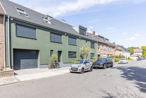 two cars parked in front of a green building at B26 Apartments - Unterwegs zu Hause in Willich