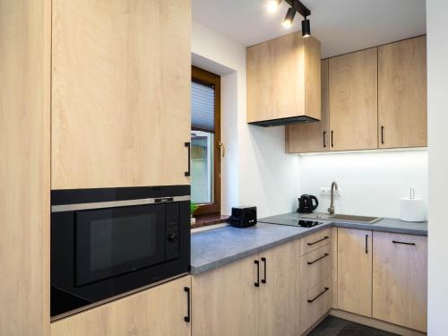 a kitchen with wooden cabinets and a black microwave at Osada turystyczna Malinów in Szczawnica