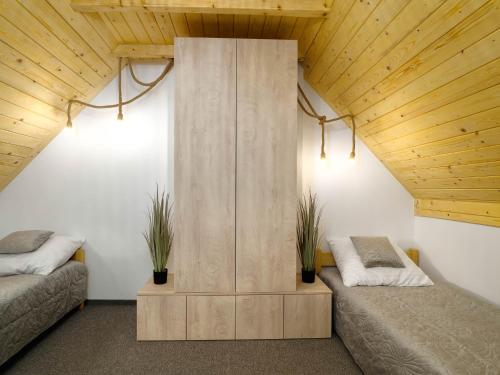 two beds in a room with wooden ceilings at Osada turystyczna Malinów in Szczawnica