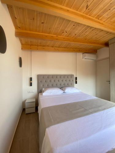 1 dormitorio con 1 cama grande y techo de madera en MEDUSA Luxury Apartments, en Finikounta
