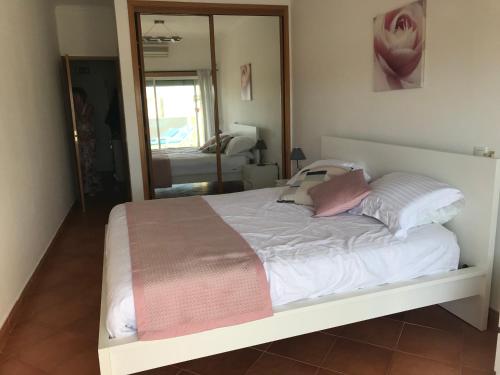 łóżko z białą pościelą i różowymi poduszkami w sypialni w obiekcie Condo do Mar Lovely first floor apartment with pool w Lagosie