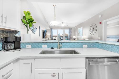 a kitchen with white cabinets and a sink at Calypso 3-406 - Paradise by the Pier in Panama City Beach