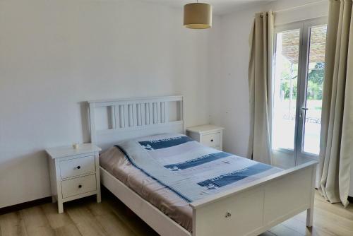une chambre blanche avec un lit et une fenêtre dans l'établissement Villa de plain pied avec BBQ et piscine, à Tavernes