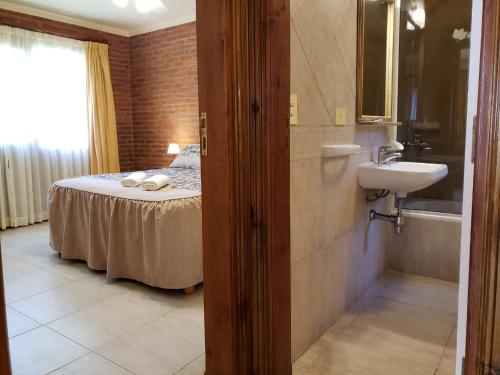 ein Bad mit einem Bett und einem Waschbecken in einem Zimmer in der Unterkunft Refugio del Bosque in Carilo