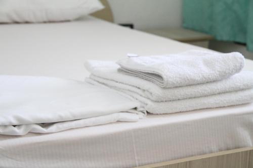 a stack of white towels sitting on a bed at Shtepi Pushimi in Durrës