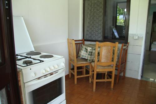 a kitchen with a stove and a table with chairs at Shtepi Pushimi in Durrës