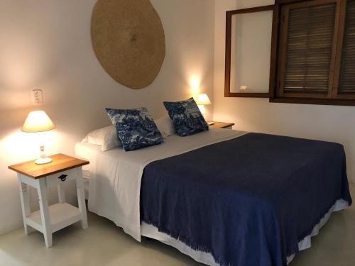 a bedroom with a bed and a table with a lamp at CASA PIÚVA in Ilhabela