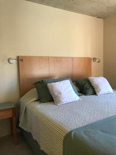 1 dormitorio con 1 cama con almohadas verdes y blancas en ALIWEN Rauli en San Martín de los Andes