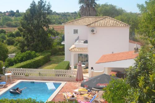 a person swimming in a swimming pool in front of a house at Casa do Poco in Armação de Pêra