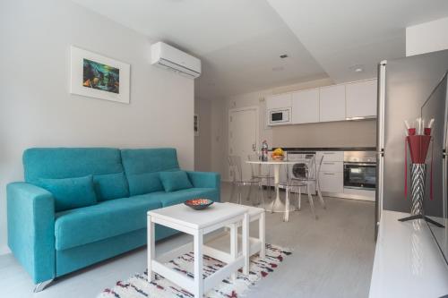 uma sala de estar com um sofá azul e uma mesa em Reinapart Valencia Beach em Valência