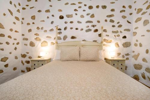 1 dormitorio con 1 cama grande con rocas en la pared en Casa Milagrito Betancuria en Betancuría