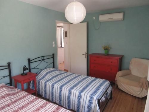 a bedroom with two beds and a chair and a dresser at George's house in Giannádes