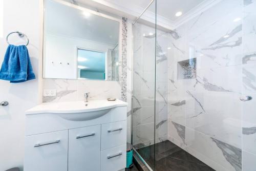 a white bathroom with a sink and a shower at Central Location - Noosa Address - Pet Friendly in Noosa Heads