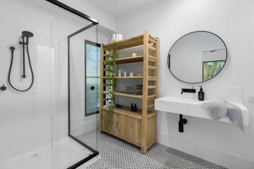 a bathroom with a sink and a mirror and a shower at BERRIMA LUXE - Noosa Hill Home - Heated Pool in Noosa Heads