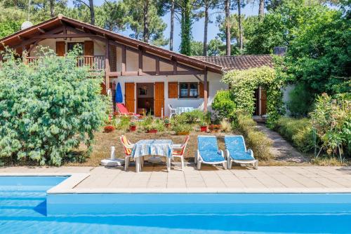 une maison avec une table et des chaises à côté d'une piscine dans l'établissement Maison entre Lac et Océan, à Biscarrosse