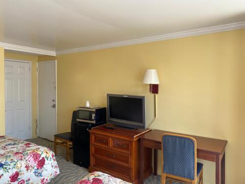 a hotel room with a desk with a television and a bed at Downbeach Inn in Atlantic City