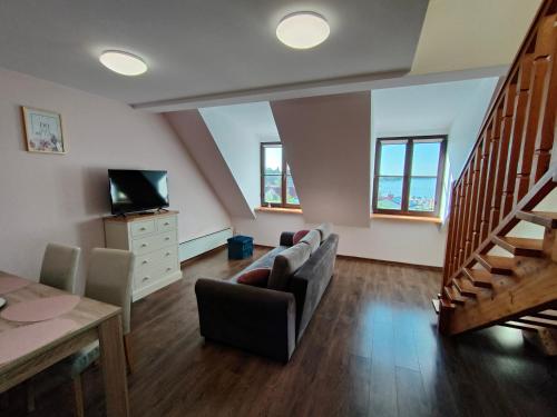 a living room with a couch and a tv and stairs at Apartament Alex in Mikołajki