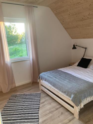 een slaapkamer met een bed, een raam en een tapijt bij Domki Kalimera Rewal in Rewal