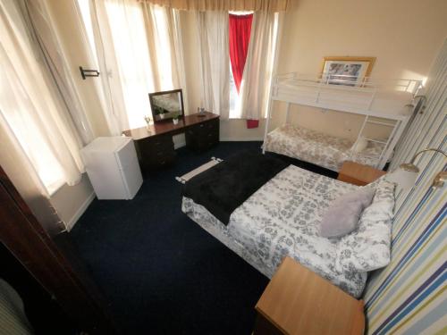 a bedroom with a bed and a desk and windows at Bourne Hall Hotel in Bournemouth