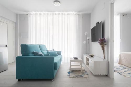 un salon avec un canapé bleu et une télévision dans l'établissement Reinapart Valencia Beach, à Valence