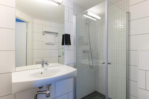 een witte badkamer met een wastafel en een douche bij Clarion Collection Hotel Plaza in Karlstad