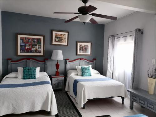 圣米格尔-德阿连德Hotel Santa Ana的一间带两张床和吊扇的卧室