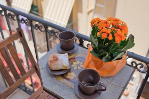 une table avec deux tasses et un vase avec des fleurs orange dans l'établissement Casa Bordonaro B (by Vacation Service), à Cefalù