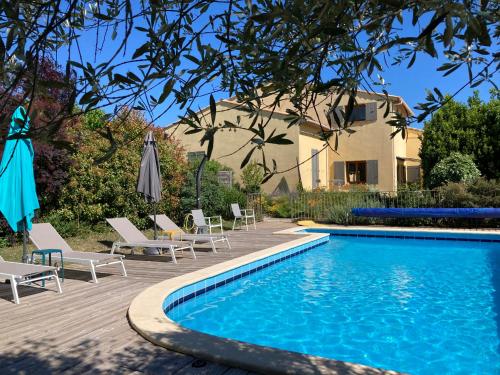 - une piscine avec des chaises et des parasols à côté d'une maison dans l'établissement L'Orée des Mages - Ma maison de vacances, à Saint-Julien-de-Cassagnas