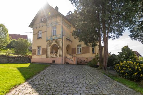 a large yellow house with a tree and a driveway at Vila Heide in Česká Kamenice