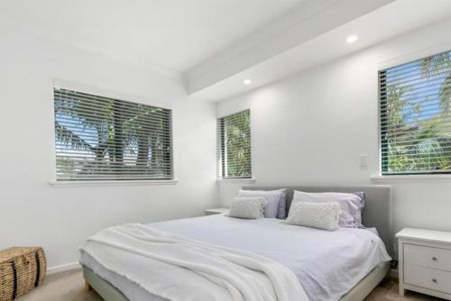 a white bedroom with a bed and two windows at HOWARD 11-7 Noosa River at your doorstep in Noosaville