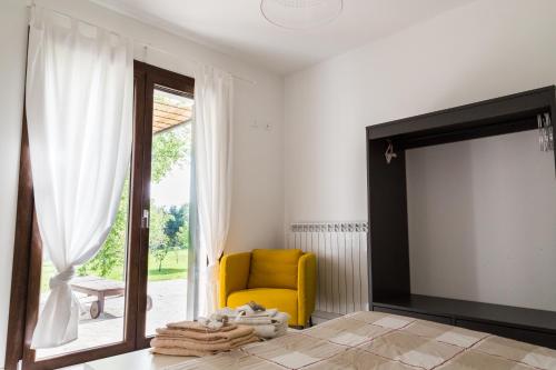 a living room with a yellow chair and a sliding glass door at all'ombra del Bagolaro in Taglio di Po