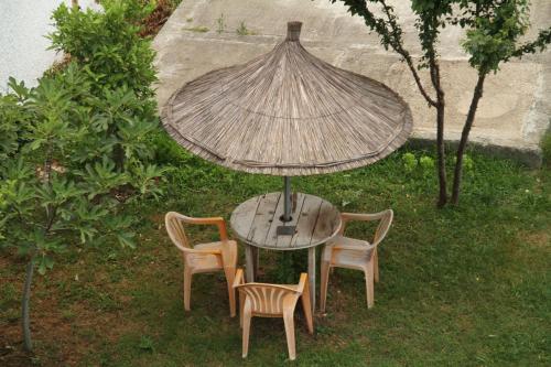 a table with two chairs and an umbrella on the grass at Shtepi Pushimi in Durrës