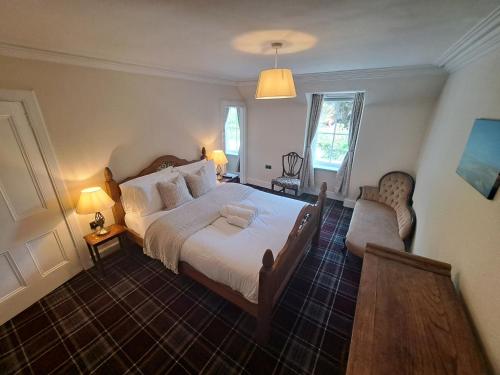 a bedroom with a large white bed and a chair at Clematis Cottage, Fortrose in Fortrose