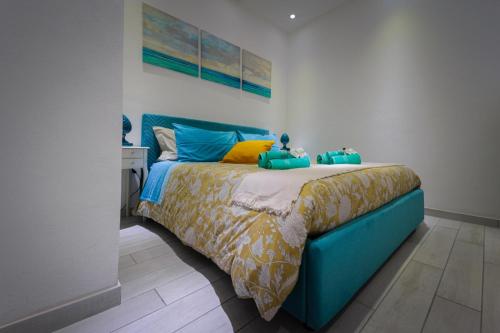 um quarto com uma cama azul com lençóis azuis e amarelos em La Casetta del Ronco1 Ortigia em Siracusa