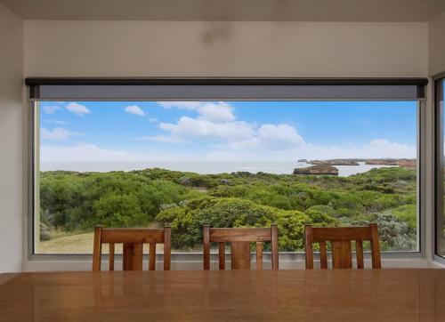 a dining room with two chairs and a large window at Martyrs Lookout - Luxury Accommodation in Peterborough
