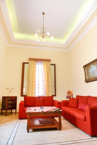 a living room with a red couch and a table at Classical Villa Archontiko D&M in Rhodes Town