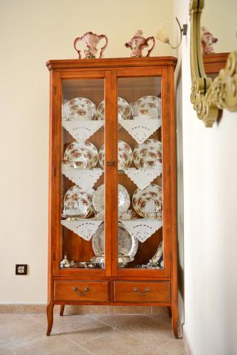 a wooden cabinet with plates and dishes in it at Classical Villa Archontiko D&M in Rhodes Town