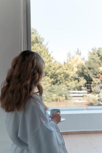 a woman looking out of a window with a cell phone at Rancho Macloy Hotel Spa & Social Events in Yautepec