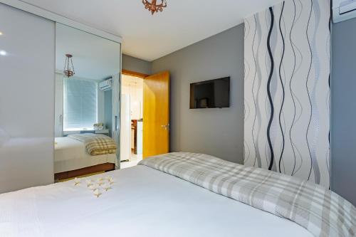 1 dormitorio con cama blanca y espejo en Premier Residence, en Brasilia