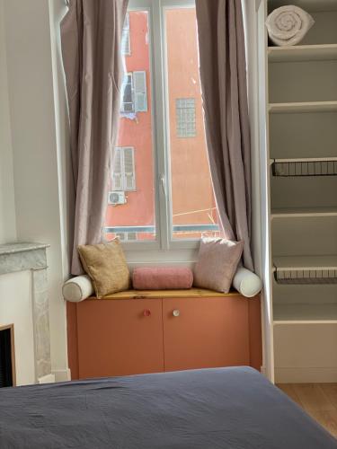 - un siège de fenêtre avec des oreillers en face d'un lit dans l'établissement F2 Glamour Centre ville historique, à Ajaccio